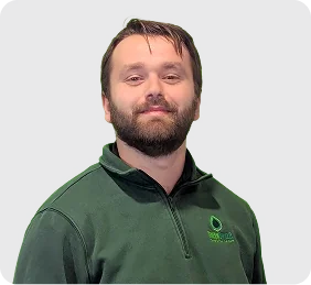 Man with a beard wearing a dark green quarter-zip pullover with a small green logo